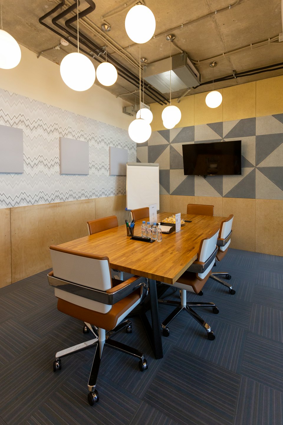 Modern meeting room with wooden table and office chairs.