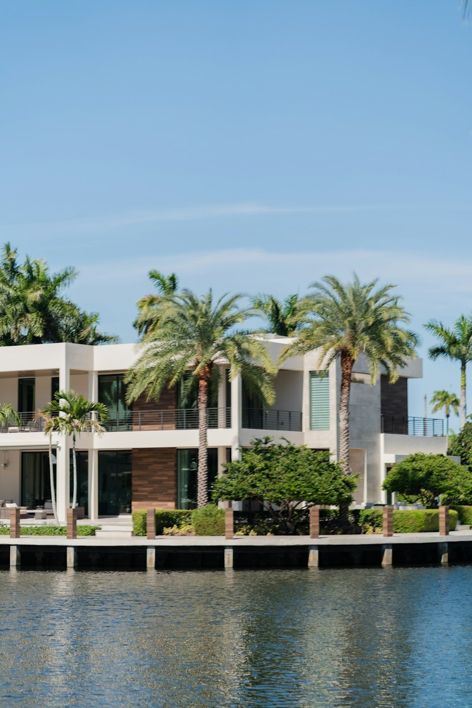 Modern waterfront house with palm trees on the water edge.